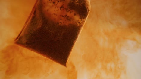 close up of tea bag diffusing in a clear glass. macro slow motion shot of the process of brewing herbal.