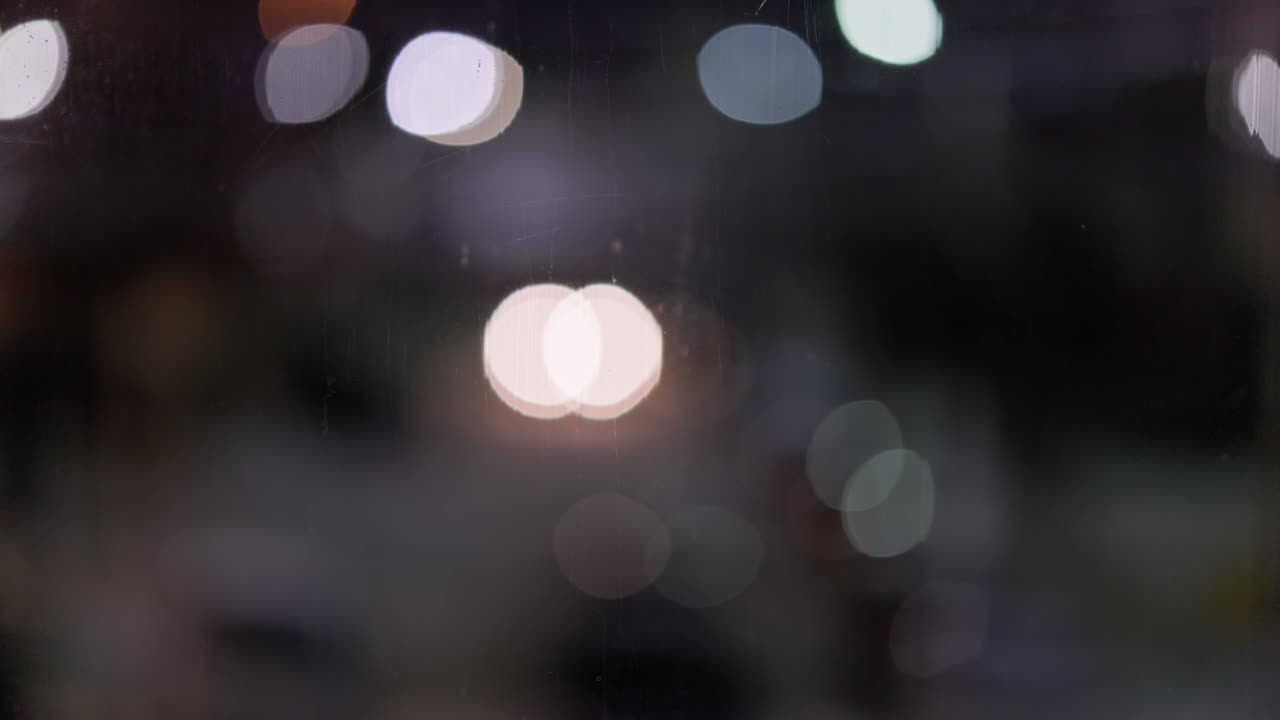 vista de cerca del vidrio de la ventana nocturna con luces de automóviles y farolas desenfocadas