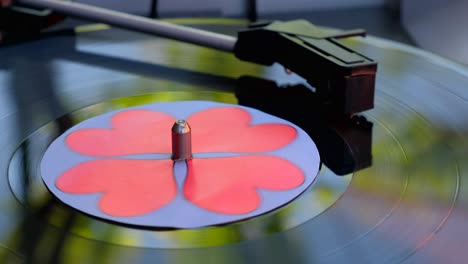 black vinyl background with red hearts in center. antiquarian record player. rotating plate and stylus with needle. popular disco trends