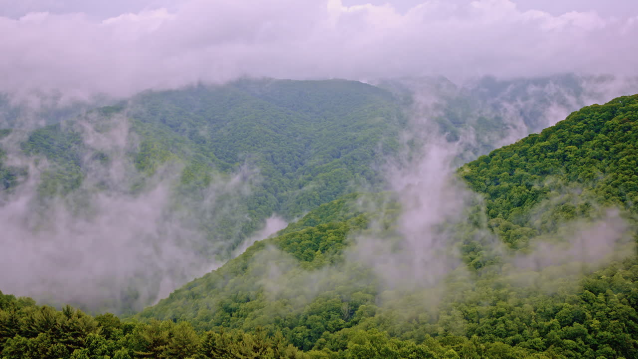 Cinematic drone shot of smoky mountains shrouded in mist and fog