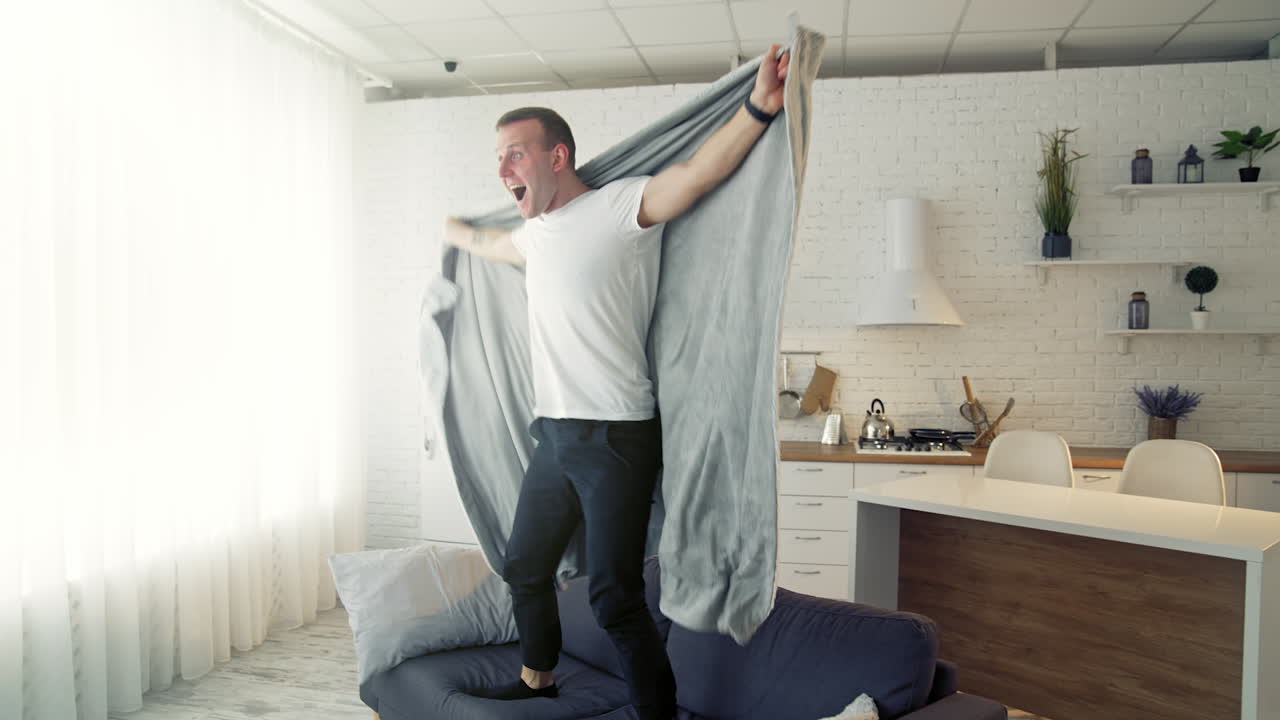 Happy man on bed. Young man waking up and began to joy waving blanket. Cheerful man recovered from the disease. Healthcare concept.
