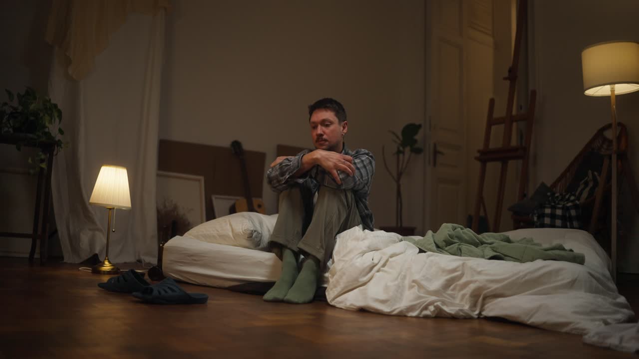 Depressed Man Sitting on Bed at Night