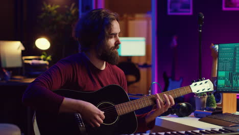 musician trying to tune the sound of his guitar in home studio