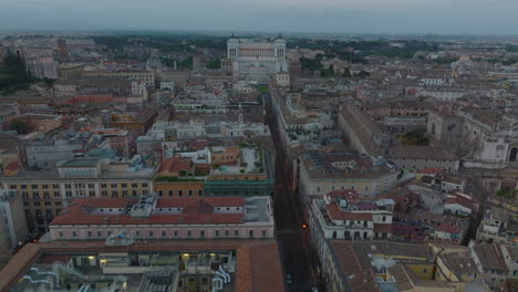 Forwards-fly-above-historic-buildings-in-city-centre,-landmarks-and-tourist-sights.-Heading-towards-Vittoriano-monument-at-twilight.-Rome,-Italy