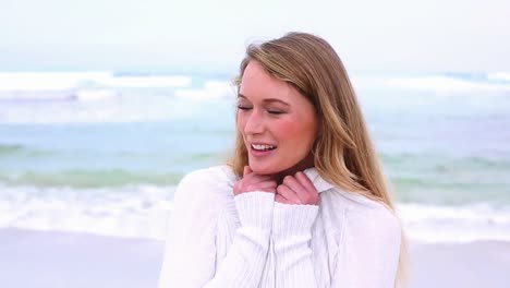 Fröhliche-Blondine-Lächelt-Am-Strand-In-Die-Kamera
