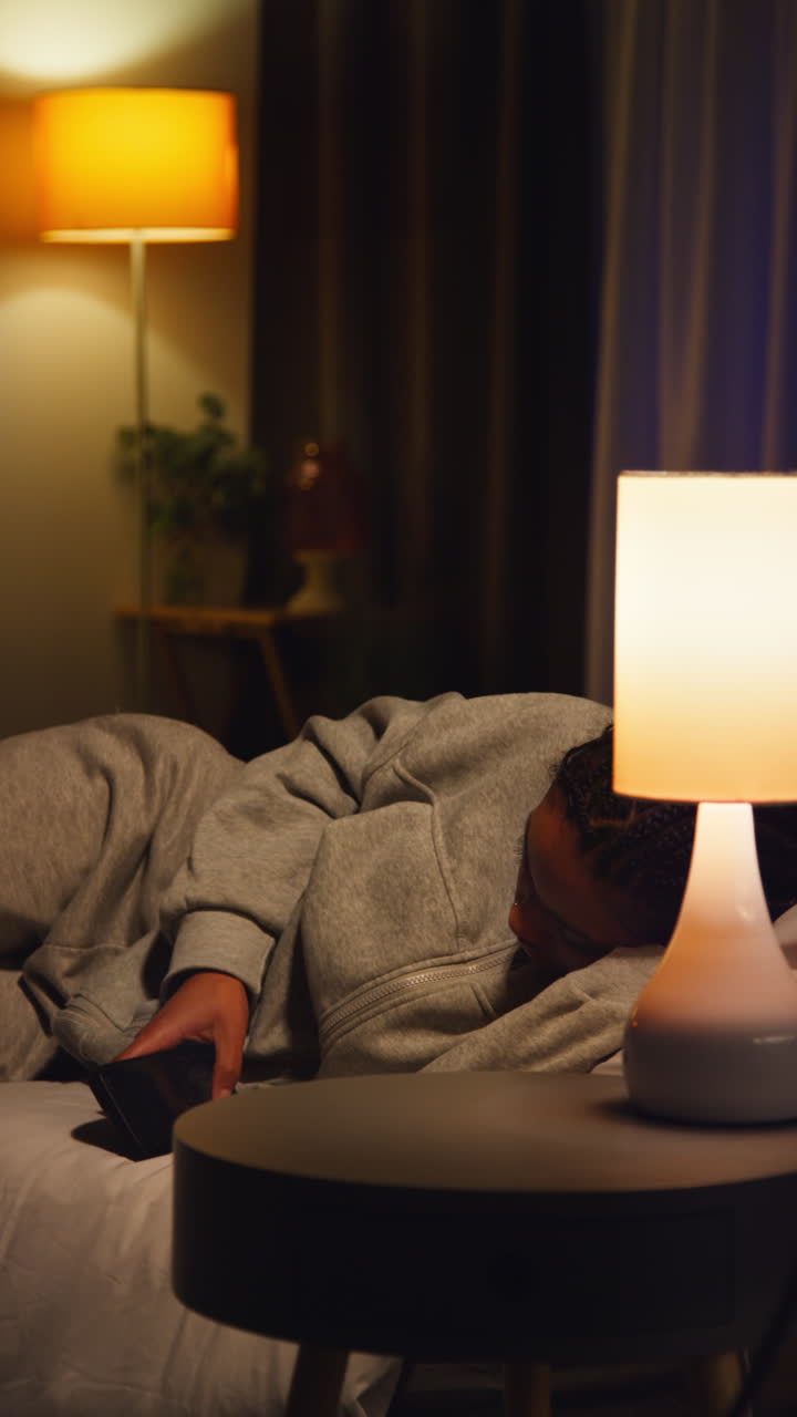 donna sdraiata a letto di notte a guardare il telefono