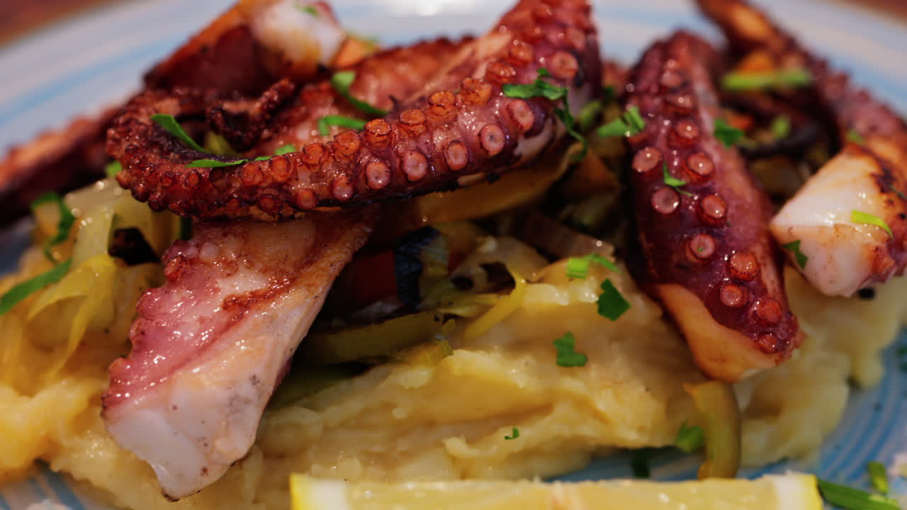 Close up of grilled octopus on a puree and a piece of lemon at a restaurant