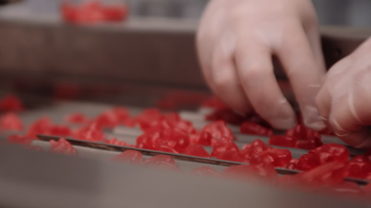 Operai in una fabbrica di produzione nutraceutica distribuiscono vitamine gommose rosse