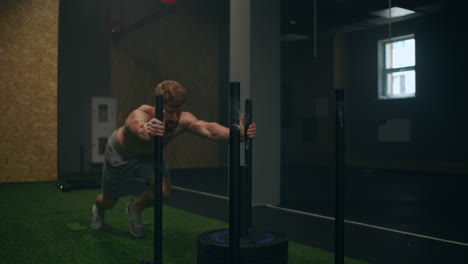 Muskulöser-Mann-Schiebt-Schlitten-Im-Fitnessstudio-Während-Des-Trainings-In-Zeitlupe