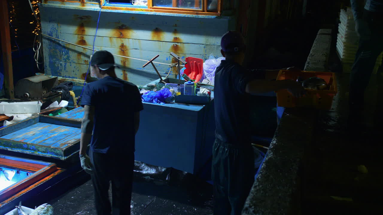 grupo de pescadores descargando bandejas llenas de pescado del barco para el comercio, tho quang, vietnam