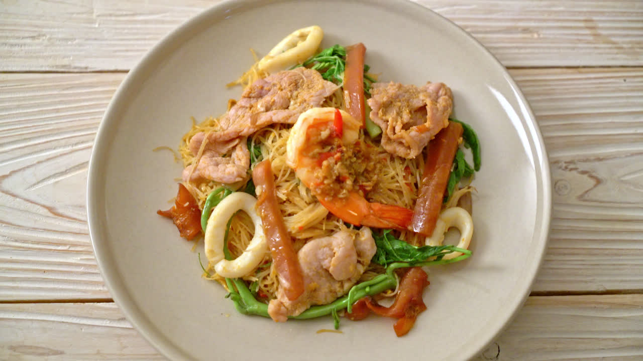 혼합 고기를 곁들인 볶음 쌀 당면과 물 미모사