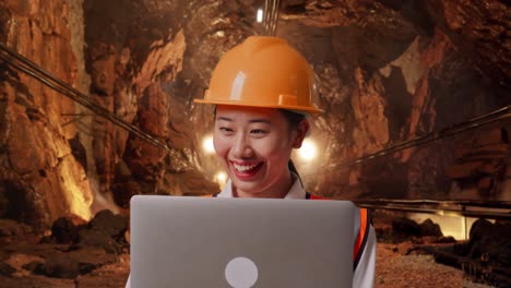 Close Up Of Asian Female Engineer With Safety Helmet Working On A Laptop In Underground Mine Tunnel