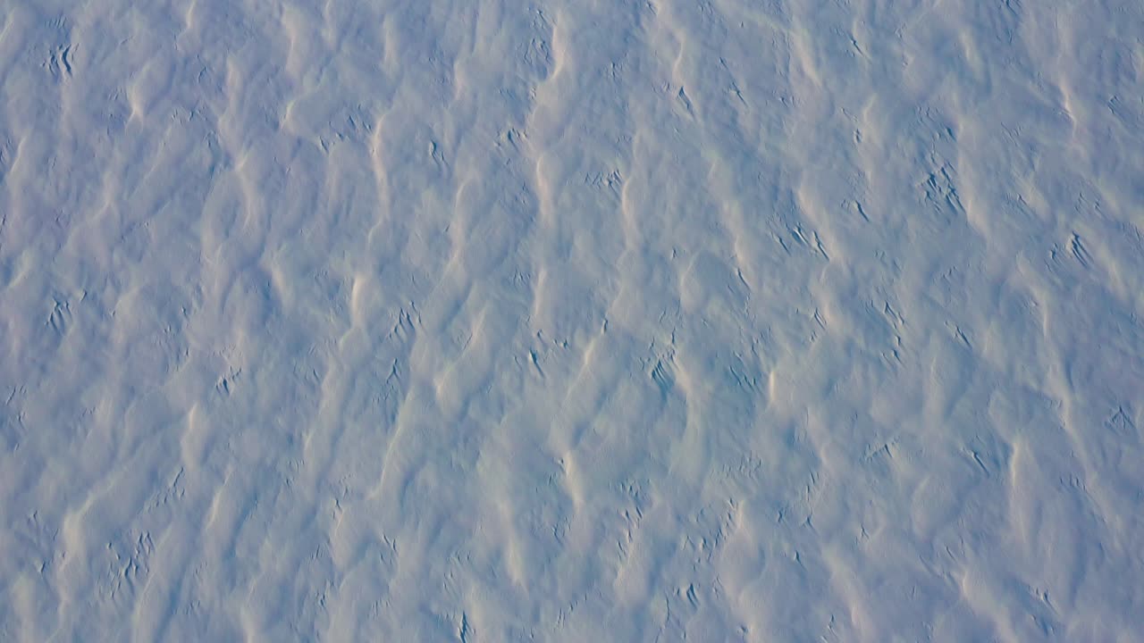 arriba hacia abajo aéreo volando hacia atrás sobre los patrones en la nieve fresca