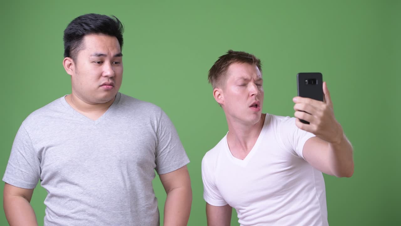 두 명의 젊은 다민족 잘생긴 남자들이 녹색 배경에 함께 있습니다.