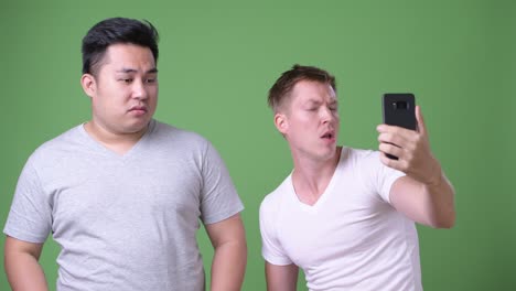 two young multi-ethnic handsome men together against green background