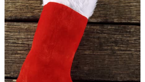 Animation-of-santa-sock-on-wooden-background-at-christmas