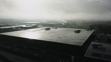 Aerial-shot-of-a-large-factory-building-in-the-morning-fog-in-the-Netherlands