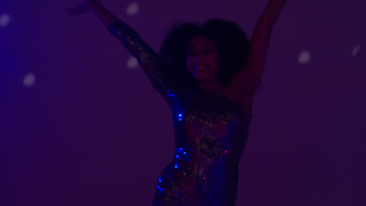 primer plano de una mujer joven en un bar nocturno o discoteca bailando con luces brillantes 9