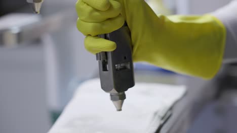 hand in gloves working on stained clothes with stain removing machine at laundry shop