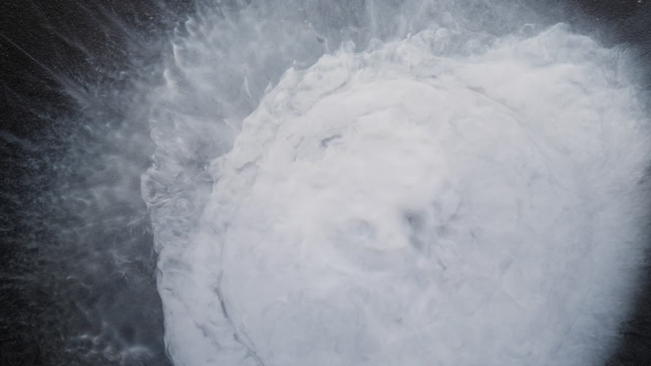 Exploding white alcoholic ink creates dynamic splash pattern in abstract macro view