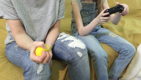 woman sitting on couch and squeezing stress ball.daughter using game console and playing video game