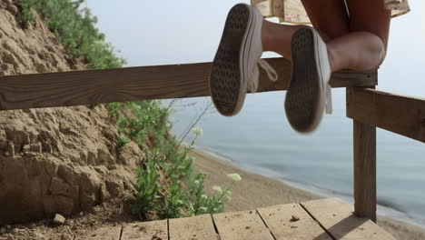 unkwown girl legs white sneakers having fun on seashore staircase close up.