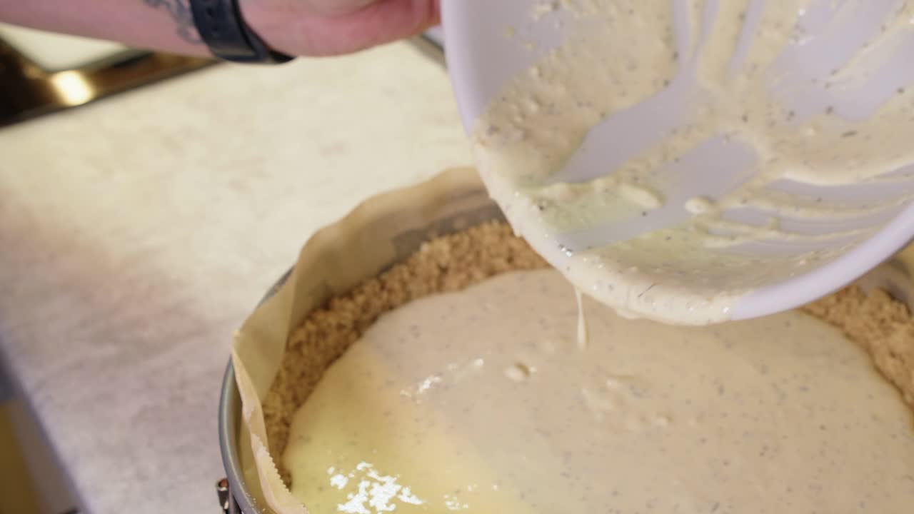 Cheesy filling poured onto crumble crust in cheesecake springform pan