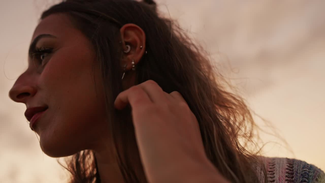 Brunette femalel in profile looking to the side while touching her hair. Slow motion low angle