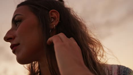 brunette femalel in profile looking to the side while touching her hair. slow motion low angle