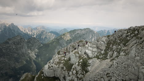 Drone-shot-of-mountain-Rombon-and-nerby-mountains,-a-group-of-hiker-climbing-up-a-hill-to-reach-the-top