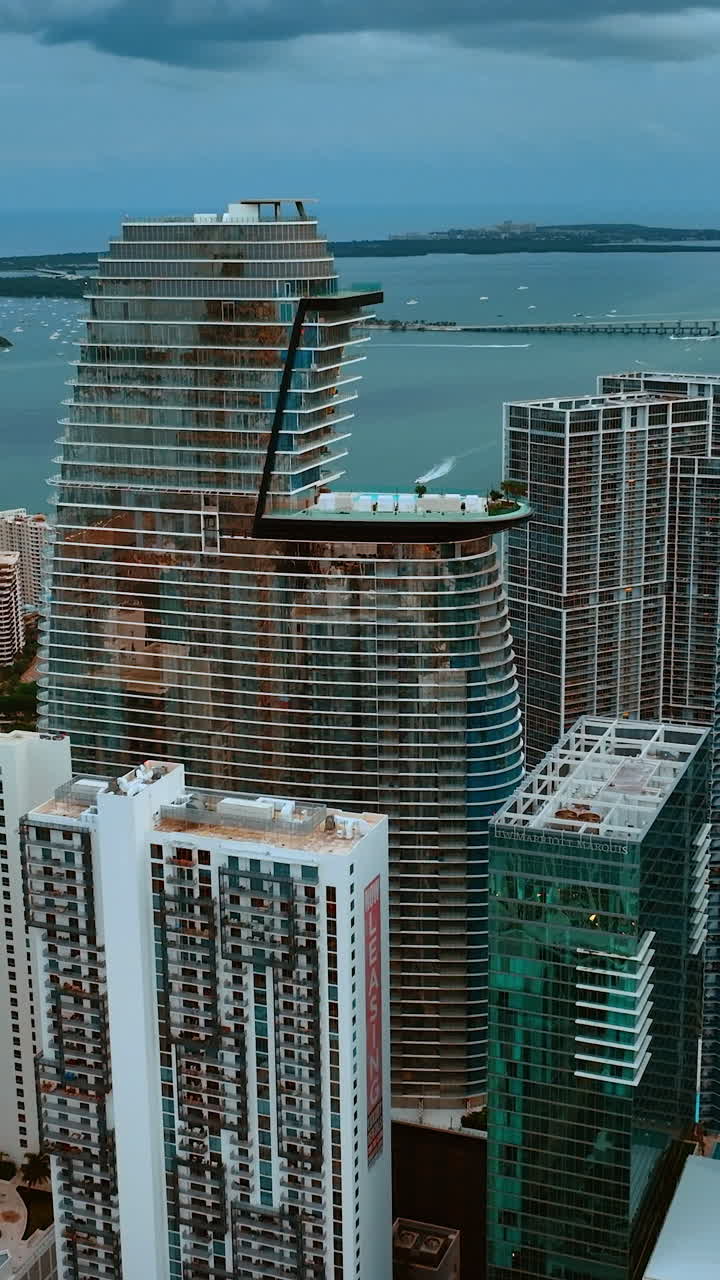 Rising above the skyscrapers on the waterfront of Miami. Opening view on Atlantic Ocean on cloudy day. Vertical video