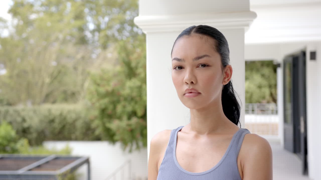 Biracial fit woman with serious expression looking at camera in garden