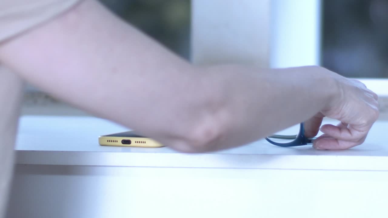Reaching for mobile phone and glasses located on window ledge