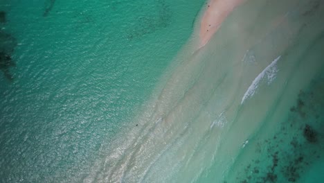 Turquoise-ocean-waters-and-sandy-shoals-with-gentle-waves,-aerial-view