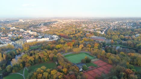 skyline of residential brussels with tennis courts and hockey pitch on top of the woluwe park - aerial view