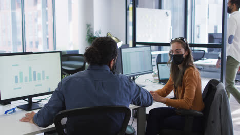 diversos colegas masculinos y femeninos en los escritorios usando computadoras usando máscaras faciales y golpeando los codos