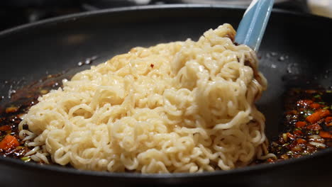 Stirring-ramen-noodles-into-the-sizzling-sauce-in-a-pan