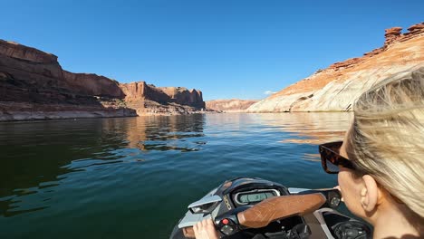 Women-drive-jet-ski-on-reservoir-Lake-Powell,-blue-sky,-Utah