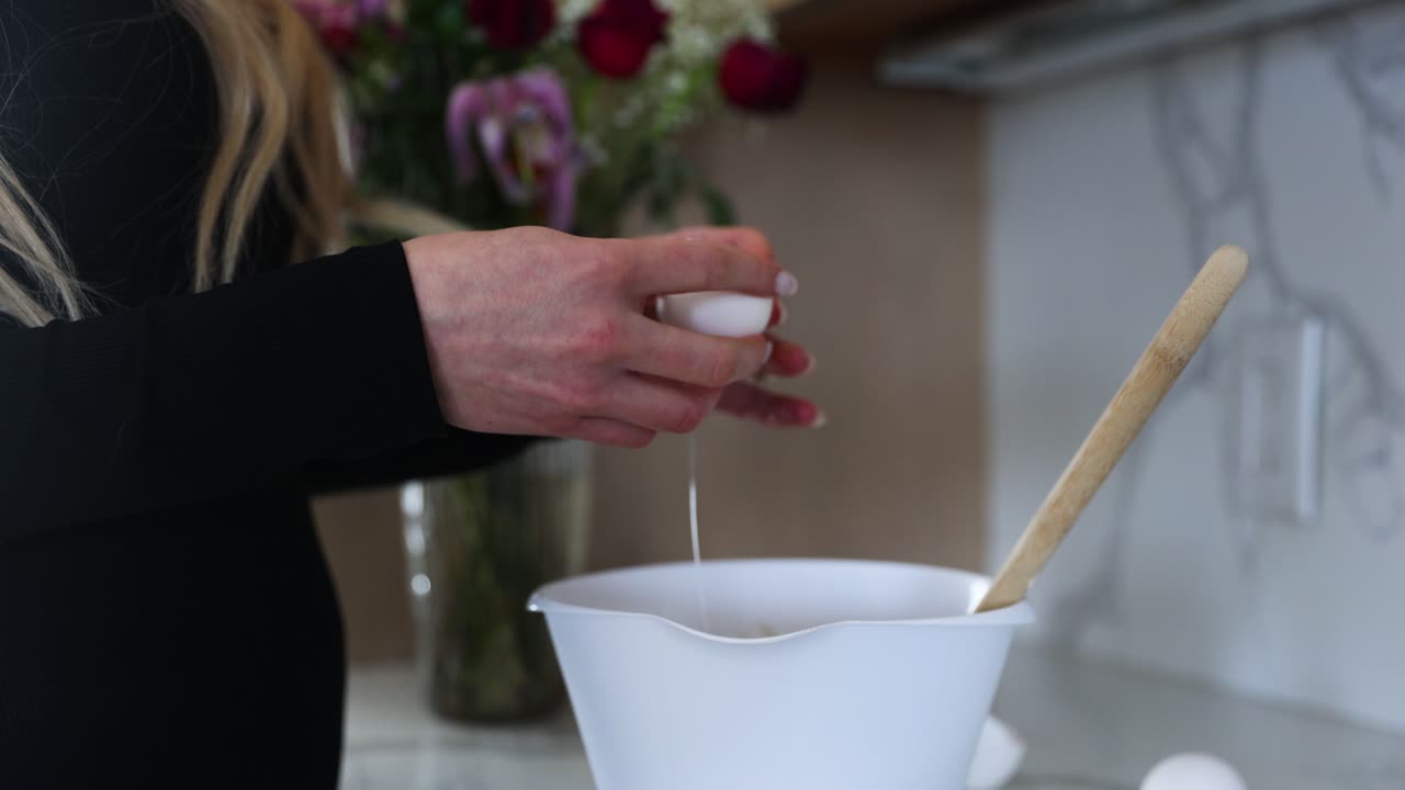 계란을 굽는 동안 그릇에 계란을 깨고 부엌에서 여성 여자