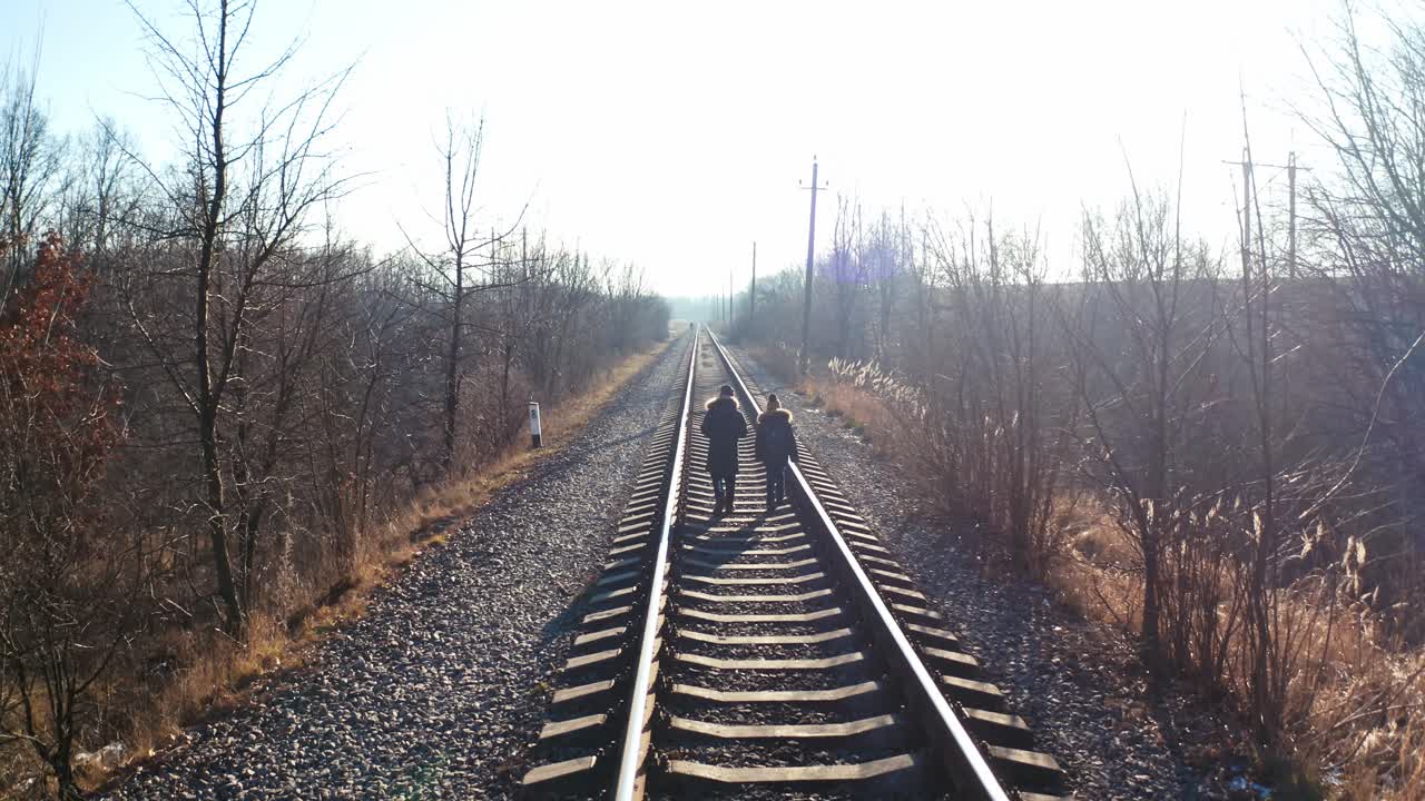 People walking on railway in forest. Traveler people walking along the railroad tracks