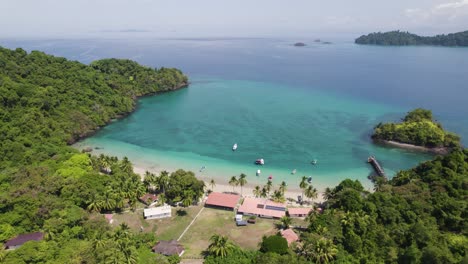 A-tropical-beach-with-clear-blue-water,-lush-greenery-and-boats-on-the-shore,-Coiba-Island