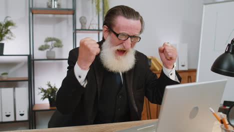 hombre de negocios ganador trabajando navegando escribiendo en el portátil en la oficina celebrando una gran lotería ganar buenas noticias
