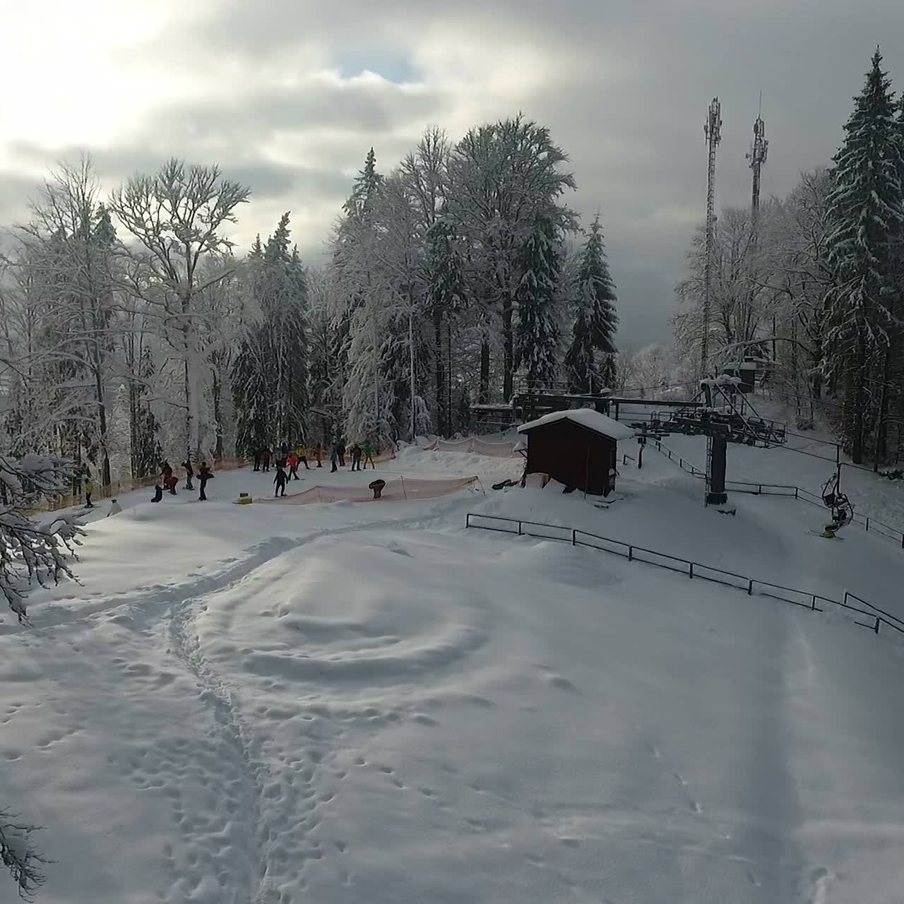 Winter alpine ski resort. Snow forest and skiers on a ski lift pov. Aerial view