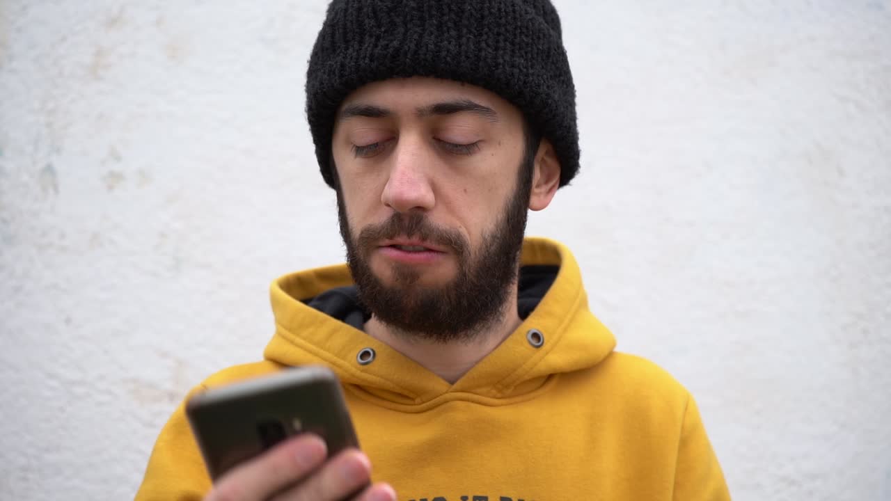 hombre guapo barbudo se enoja mientras sostiene el teléfono inteligente
