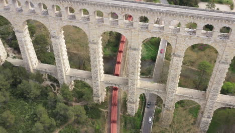 cargo train passing under the bridge aqueduct de roquefavour france aerial view