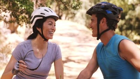 una pareja de jóvenes sonrientes montando una bicicleta.