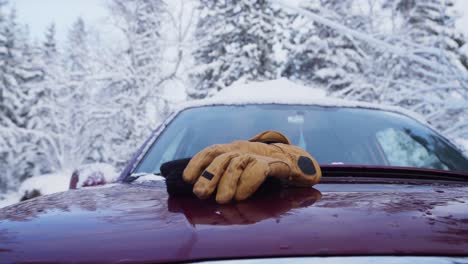 Gorro-De-Punto-Y-Un-Par-De-Guantes-Tirados-En-El-Capó-Del-Coche-Con-Techo-Cubierto-De-Nieve-En-Invierno