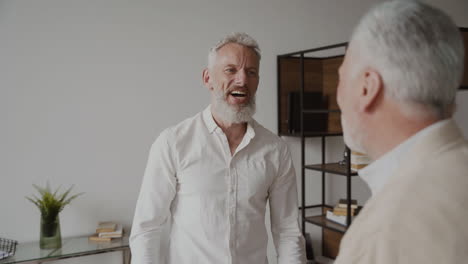 Two-Happy-Senior-Men-Friends-Talking-And-Laughing-At-Home