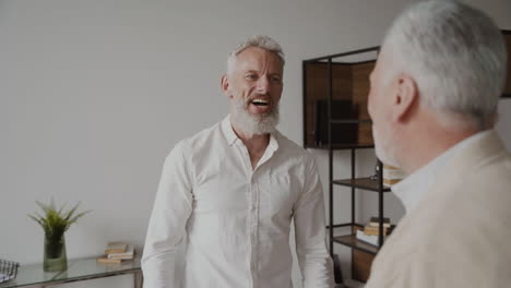 two happy senior men friends talking and laughing at home