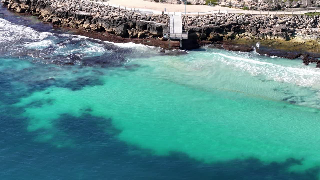 Panoramica aerea cinematografica del molo di North Beach a Perth, Australia Occidentale, con un uomo che pesca dal bordo dell'acqua